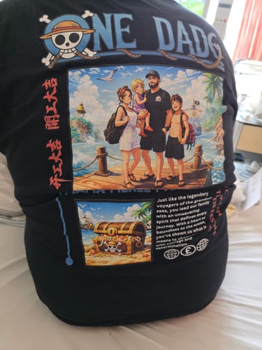 Kunde zeigt die Rückseite seines personalisierten schwarzen 'ONE DAD' T-Shirts mit buntem Anime-Druck.