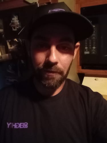 Reviewer in a close-up photo wearing the black DCG88 hat in a dimly lit room.