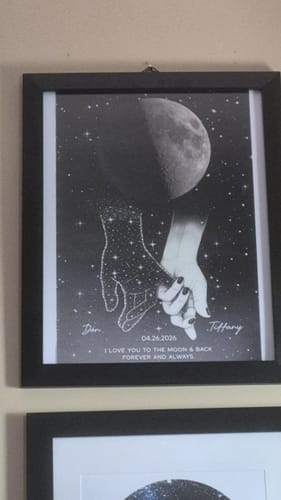Customer's personalized memorial poster framed on a wall, showing two holding hands under a moon phase.
