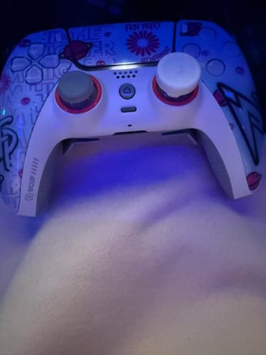Ein Kunde zeigt einen PS5-Controller mit einem bunten Design und den installierten weißen RZ Controller Sticks.