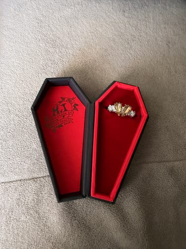 Customer's Promise Ring presented in its open, coffin-shaped box with a red interior.