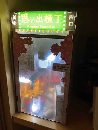 Customer's completed and illuminated Omoide Yokocho Book Nook Kit, displayed on a shelf.