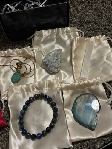 Reviewer's AuraBloom Subscription Box contents, including a crystal bracelet, necklace, and assorted raw stones.