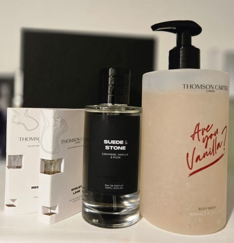 Reviewer's Suede & Stone Eau de Parfum bottle shown with a body wash and two fragrance samples from the same collection.