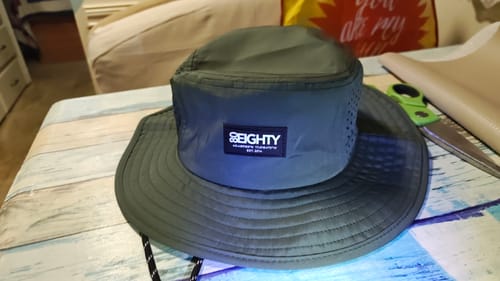 Reviewer's green 80Eighty® HQ Bucket Hat sitting on a tabletop, ready for a trip.