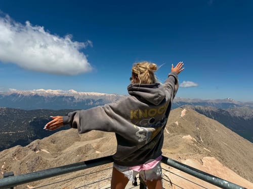 Reviewer from behind wearing the Fade Fleece Hoodie with arms outstretched on a mountaintop.