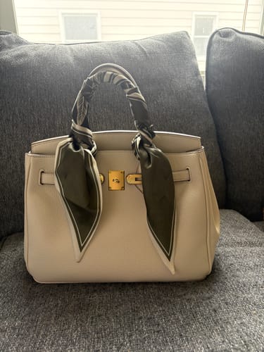 Customer's beige Warkin Bag sitting on a gray couch, with a patterned scarf wrapped around the top handle.