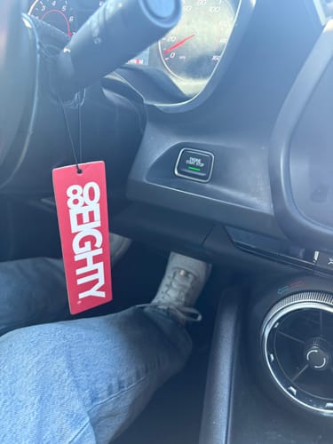 Customer's red 80Eighty Air Freshener hanging from the steering column inside a car.