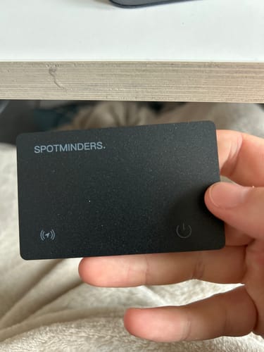 Customer holding the slim, black SPOTMINDERS. Tracking Card in their hand.