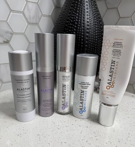 Reviewer's Alastin Restorative Skin Complex serum displayed with other Alastin skincare products on a counter.
