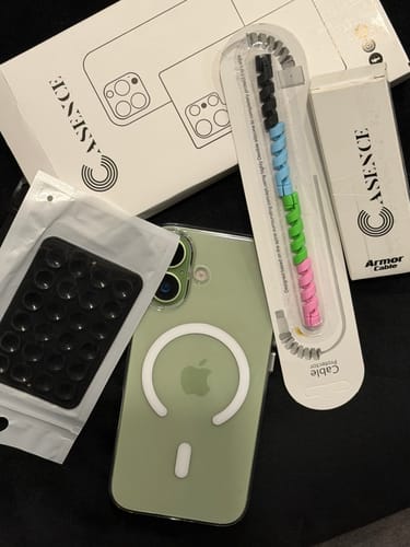 Customer's Anti Yellow Magsafe Clear Case on a green iPhone, with its packaging and accessories laid out on a table.