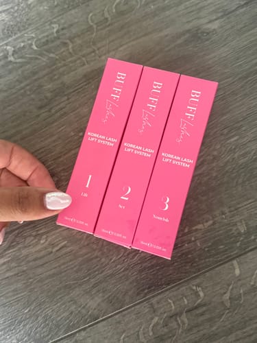 Reviewer's hand holding the three pink boxes of the Buff Lashes Korean Lash Lift System.
