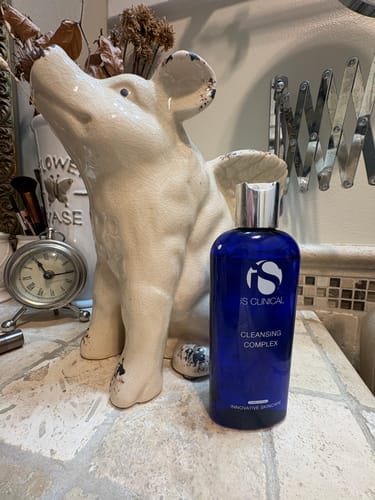 Reviewer's iS Clinical Cleansing Complex bottle on a bathroom vanity.