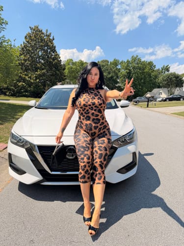Reviewer posing outdoors in the flattering, leopard-print Naked Print Halter Capri Jumpsuit.