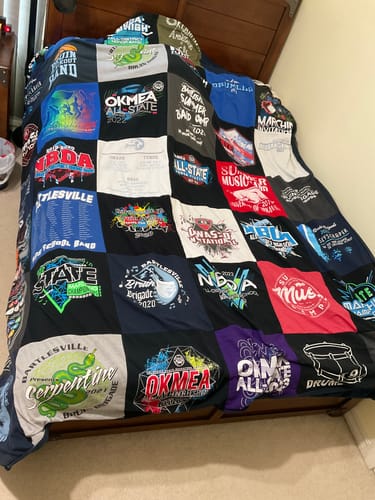 Customer's custom Project Repat T-Shirt Quilt made of colorful shirts and draped over a bed.