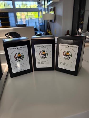 Reviewer's Peru, Bali, and Mexico coffee boxes from the Best Sellers Sample Pack on a counter.