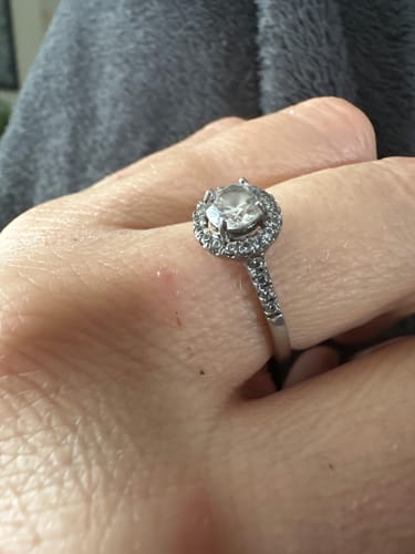 Customer's hand wearing the shiny Round Halo Solitaire Ring, highlighting the large center stone and detailed pavé band.