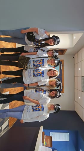 Customers at a hen party posing in a line wearing their matching custom-printed unisex t-shirts.