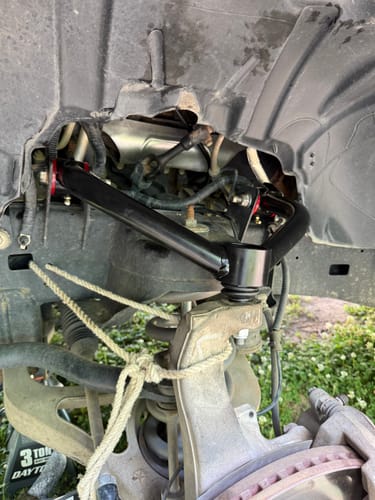 Customer's black Upper Control Arm installed in a truck's wheel well, showing the improved ball joint angle.