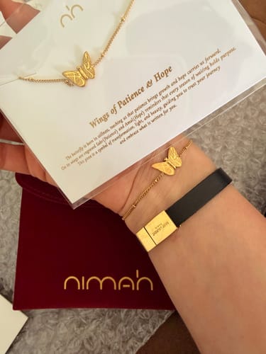 Customer wearing the gold-colored Patience & Hope Bracelet on their wrist, holding the product's packaging.