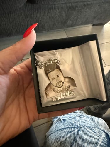 Customer holds a photo engraved pendant necklace in its gift box, showing a portrait and the name 'Uncle Mike'.