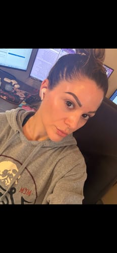 Reviewer in a grey hoodie showing off her glowing skin after using The Micro Infusion System.