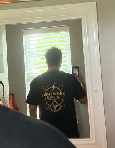 Customer showing the back of their black Custom T-Shirt with a yellow business logo printed on it.