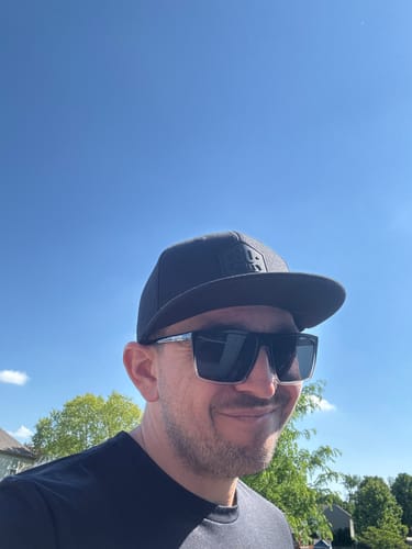 Reviewer smiling outdoors while wearing the 80Eighty® All Black Hat.