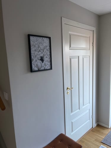 Customer's 'The Black Sheep' art print in a black frame, hanging on a grey wall next to a white door.