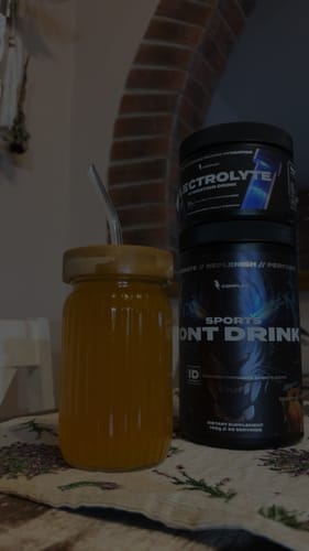 Reviewer's tub of Sports Iont Drink next to a glass of the mixed, orange beverage.