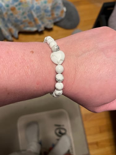 Customer's wrist wearing a white beaded Howlite bracelet with a central heart bead.