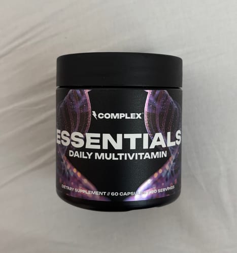 Customer's black jar of Complex Essentials Daily Multivitamin on a bed.