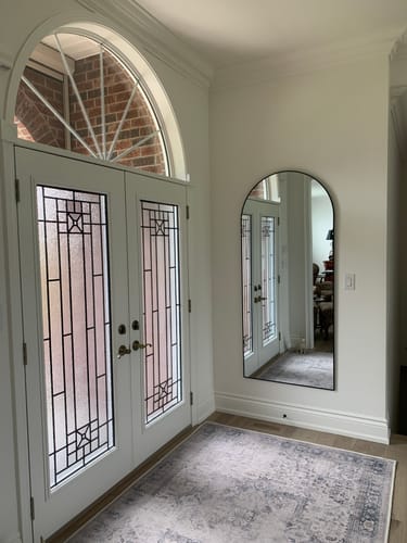 Customer's black full-length arch mirror mounted on a wall in a home entryway.