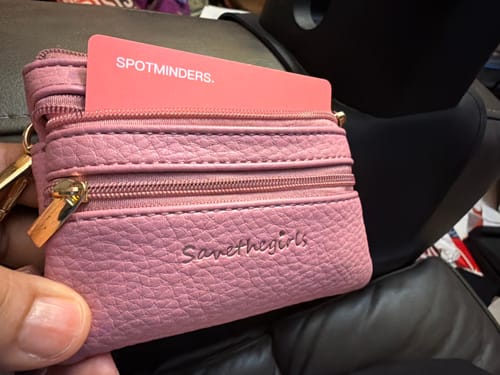 Customer holding a small pink wallet with the SPOTMINDERS Tracking Card visible in a pocket.