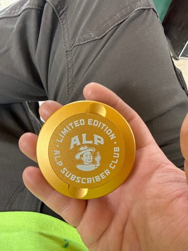 Reviewer holding the gold Subscriber Club Travel Tin in their palm, showing the limited edition logo.