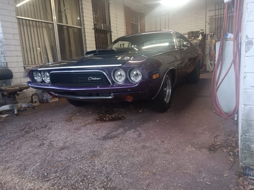 Customer's classic purple Dodge Challenger in a garage, with the catch can kit installed.