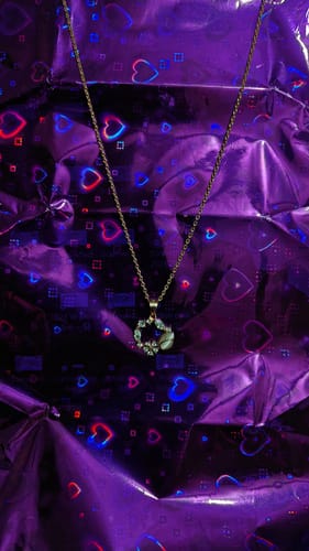 Customer's Rose Gold Drop Wreath Pendant with its link chain, shown against a shiny, purple holographic background.