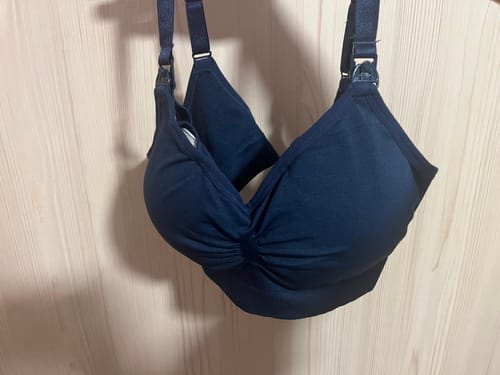 Customer's dark blue Lovemère Seamless Nursing Bra hanging against a wooden wall.