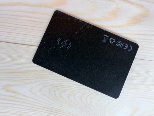 Reviewer's black SPOTMINDERS Tracking Card on a wooden surface, showing the charging and regulatory symbols.
