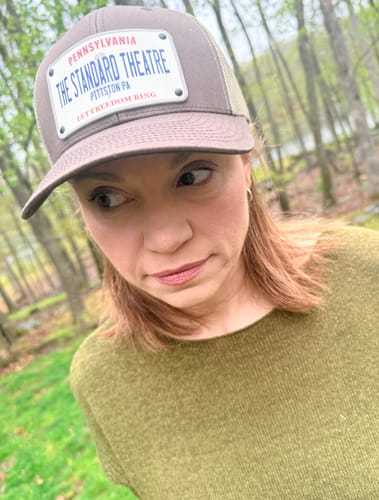 Reviewer wearing a grey Pennsylvania Plate Hat with a custom 'The Standard Theatre' patch outdoors.