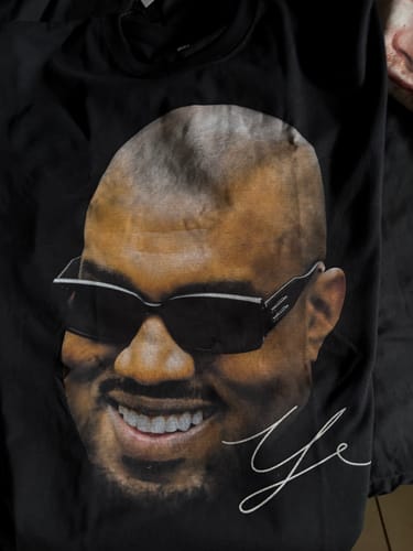 Reseñador mostrando un primer plano de la camiseta negra Ye BIG HEAD T-Shirt.
