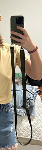 Cliente mostrando seu celular em uma case Aurora Verde Musgo com a alça pendurada.