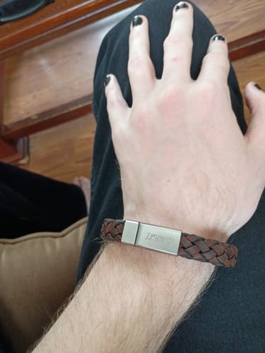 Customer wearing the braided brown leather bracelet with a silver engraved clasp on their wrist.