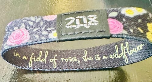 Close-up of a customer's 'In a Field of Roses Bracelet' with a floral exterior and inspirational message on the interior.
