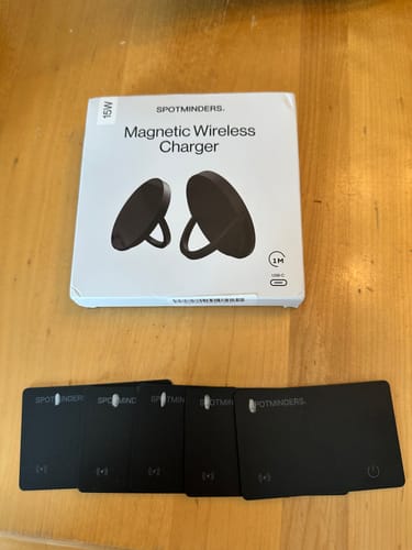 Customer's five black SPOTMINDERS Tracking Cards and the charger packaging laid out on a wooden table.