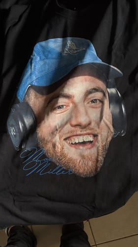 Primer plano de la camiseta negra Mac Miller BIG HEAD de un cliente, mostrando el estampado gráfico.