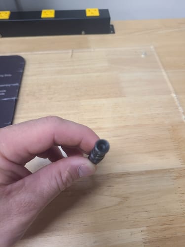 Close-up of a reviewer holding a small, broken piece of the black AR Takedown Tool.