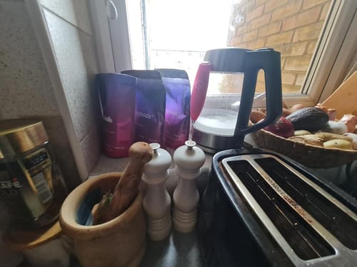 Reviewer's collection of Rainbow Dust pouches sitting on a kitchen counter next to a kettle.