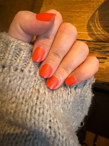 Hand einer Kundin, die die Red Stilettos UV-Gel-Folien mit einem matten Finish trägt.