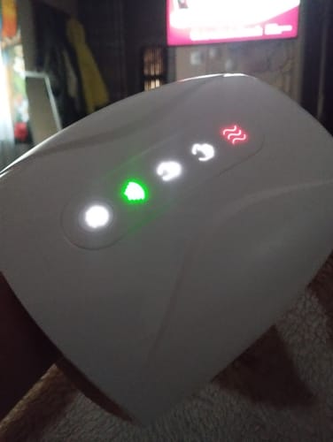 A vásárló bekapcsolt HandCare+ Kézmasszírozója, melynek kezelőpaneljén zöld és piros jelzőfények világítanak.